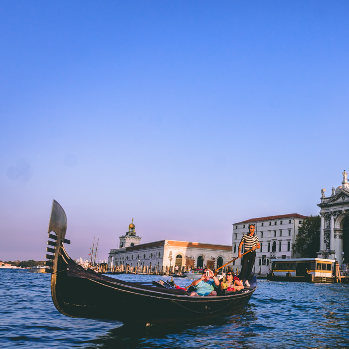Un gondoliere con turisti in un canale di Venezia con il Palazzo Ducale sullo sfondo